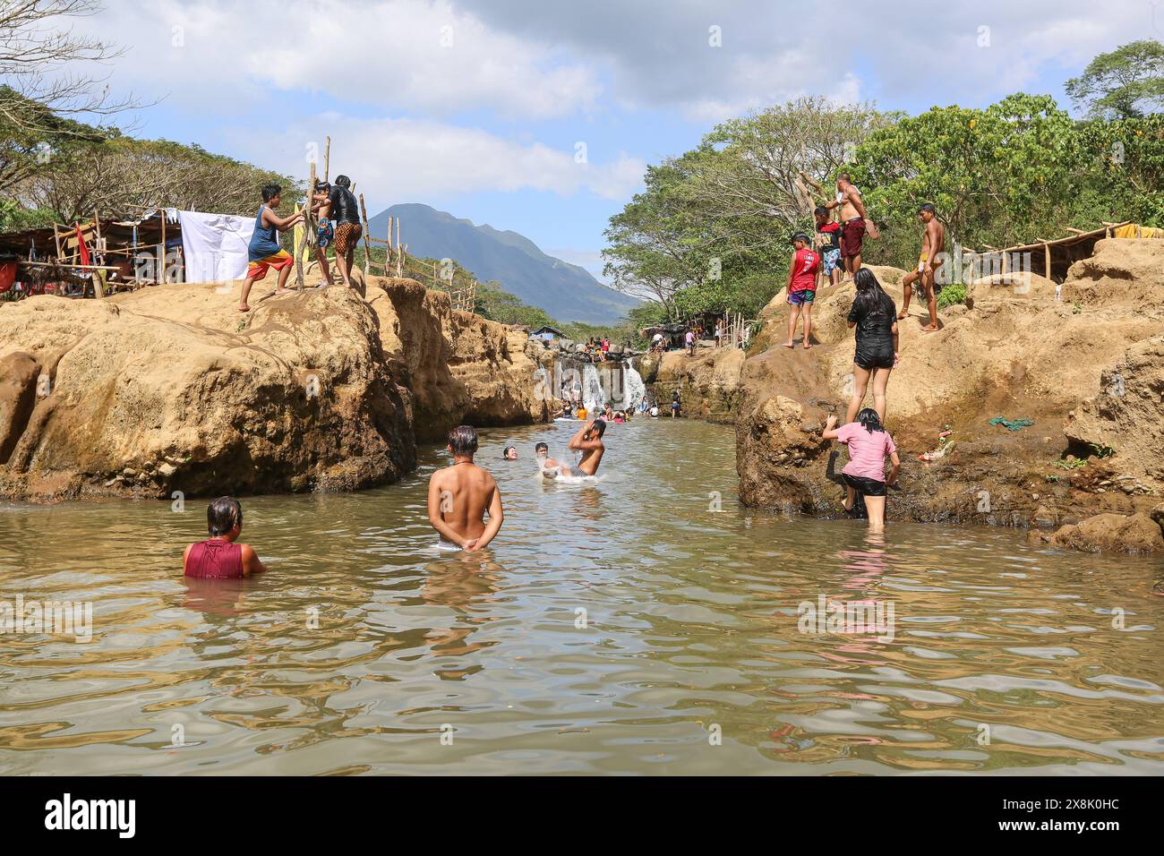 Dolores, Philippines. May 25,2024: Filipinos flock to streams that have not dried up to escape cities' stifling heat. In Calabarzon, some find refuge at Paeng Falls, a new destination created by Typhoon Paeng(2022). Streaming from Mount Banahaw, a sacred mountain prone to landslide, erosion & destructive flashfloods, Lagnas riverbed subsided to form these waterfalls highly appreciated as the archipelago & Southeast Asia suffer of severe heatwave & drought due to El Nino which will end with tropical depression Aghon, first storm to hit the country this year. Credit: Kevin Izorce/Alamy Live News Stock Photo