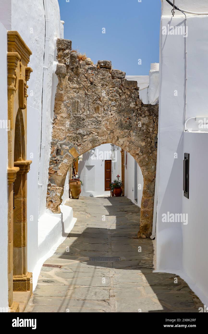 typical greek village street, houses with white exterior wall and arch of tuff stones, Lindos rhodes summer holiday destination Stock Photo