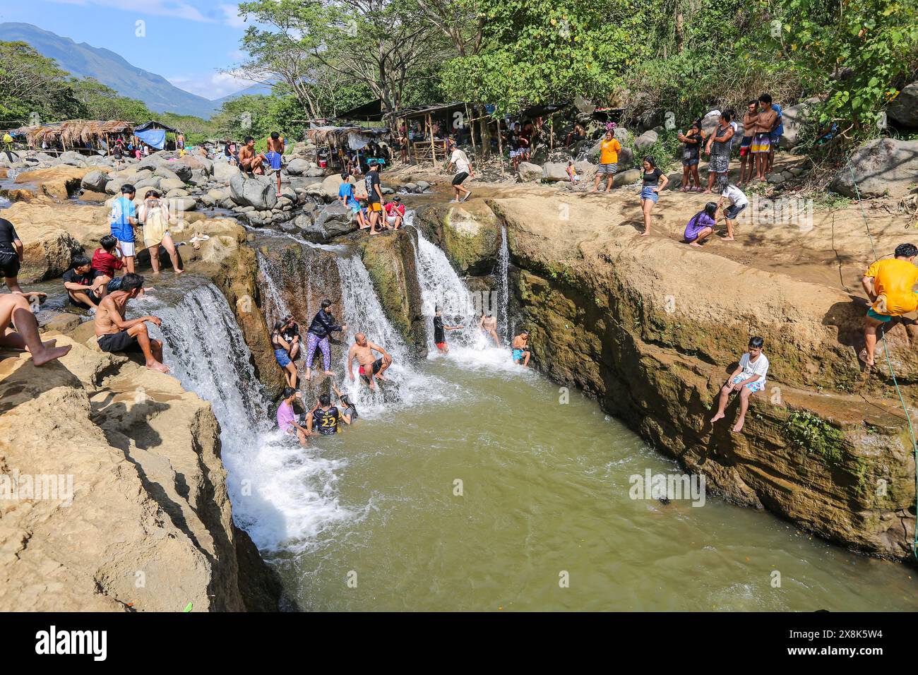 Dolores, Philippines. May 25,2024: Filipinos flock to streams that have not dried up to escape cities' stifling heat. In Calabarzon, some find refuge at Paeng Falls, a new destination created by Typhoon Paeng(2022). Streaming from Mount Banahaw, a sacred mountain prone to landslide, erosion & destructive flashfloods, Lagnas riverbed subsided to form these waterfalls highly appreciated as the archipelago & Southeast Asia suffer of severe heatwave & drought due to El Nino which will end with tropical depression Aghon, first storm to hit the country this year. Credit: Kevin Izorce/Alamy Live News Stock Photo