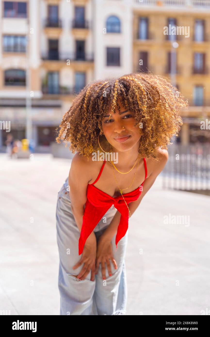 Vertical photo of a cute beauty woman with curly hair looking at camera in the city Stock Photo