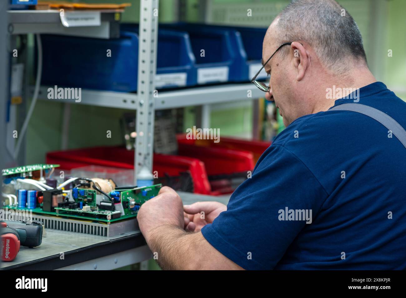 Perm, Russia - May 23, 2024: male worker assembling electronic equipment in a workshop Stock Photo