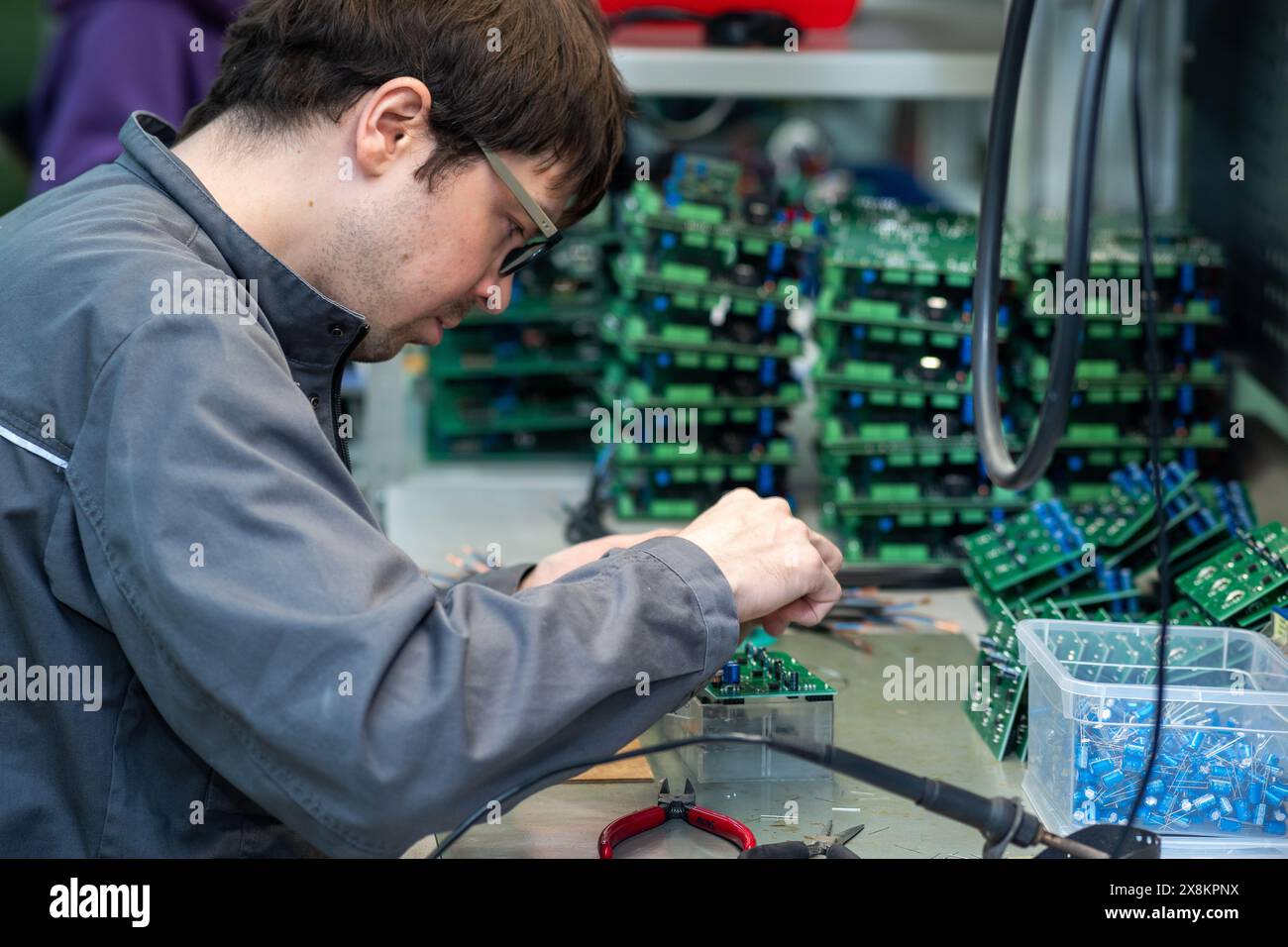 Perm, Russia - May 23, 2024: worker assembling electronic equipment in a workshop Stock Photo