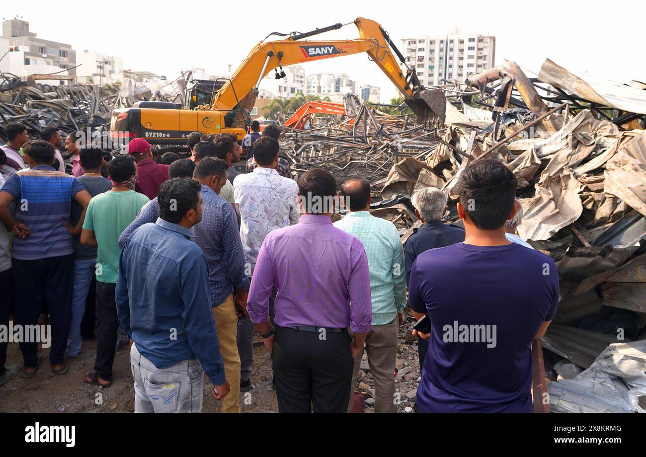Rajkot. 26th May, 2024. People watch as machines remove burnt debris after a fire broke out in an entertainment park at Rajkot district of India's western state of Gujarat, May 26, 2024. The death toll in Saturday's fire in India's western state of Gujarat has risen to 28 from 24, a local fire department official said on Sunday. Credit: Str/Xinhua/Alamy Live News Stock Photo