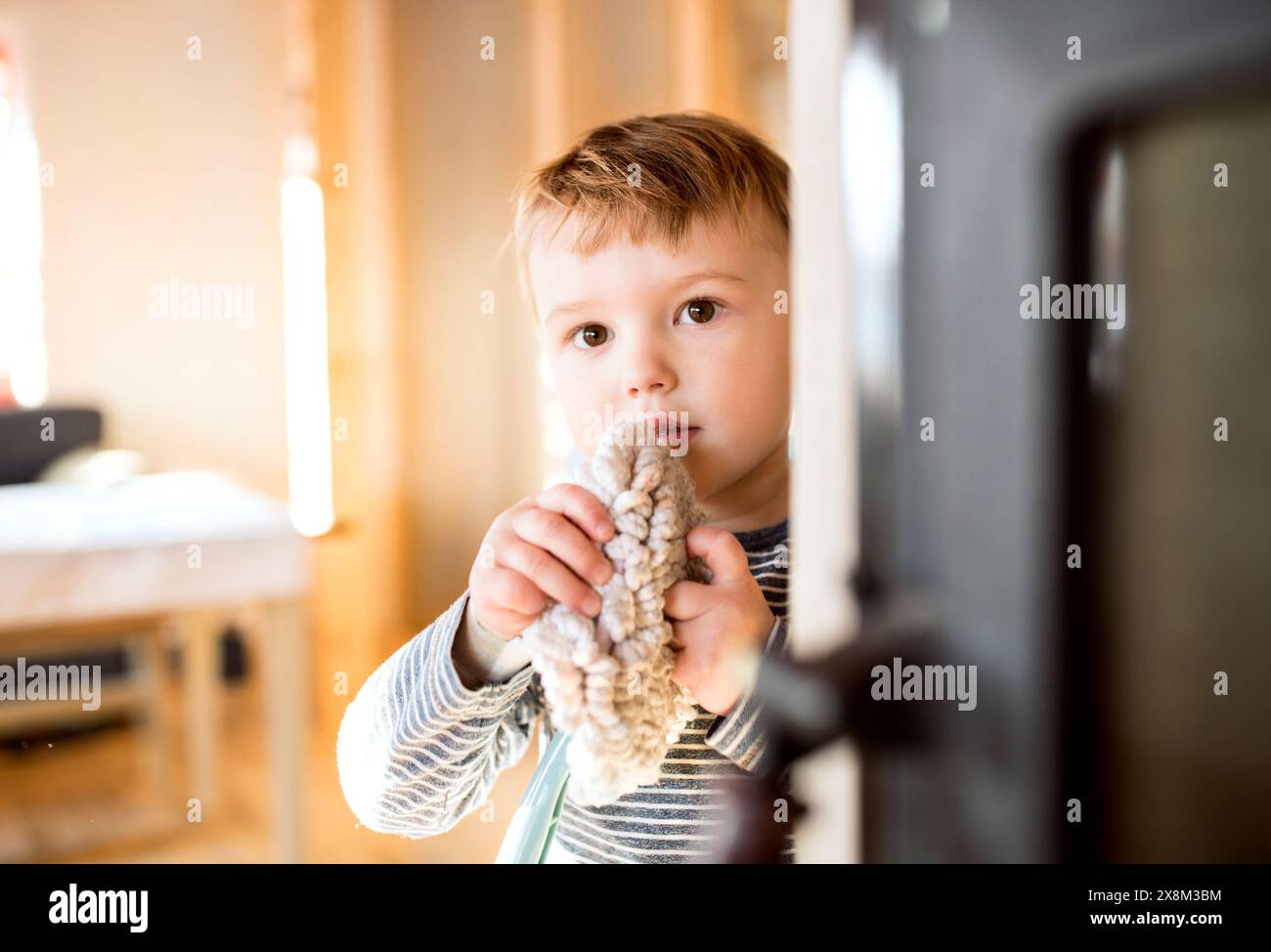 Little boy helping mother with hosehold chores, dusting cleaning their