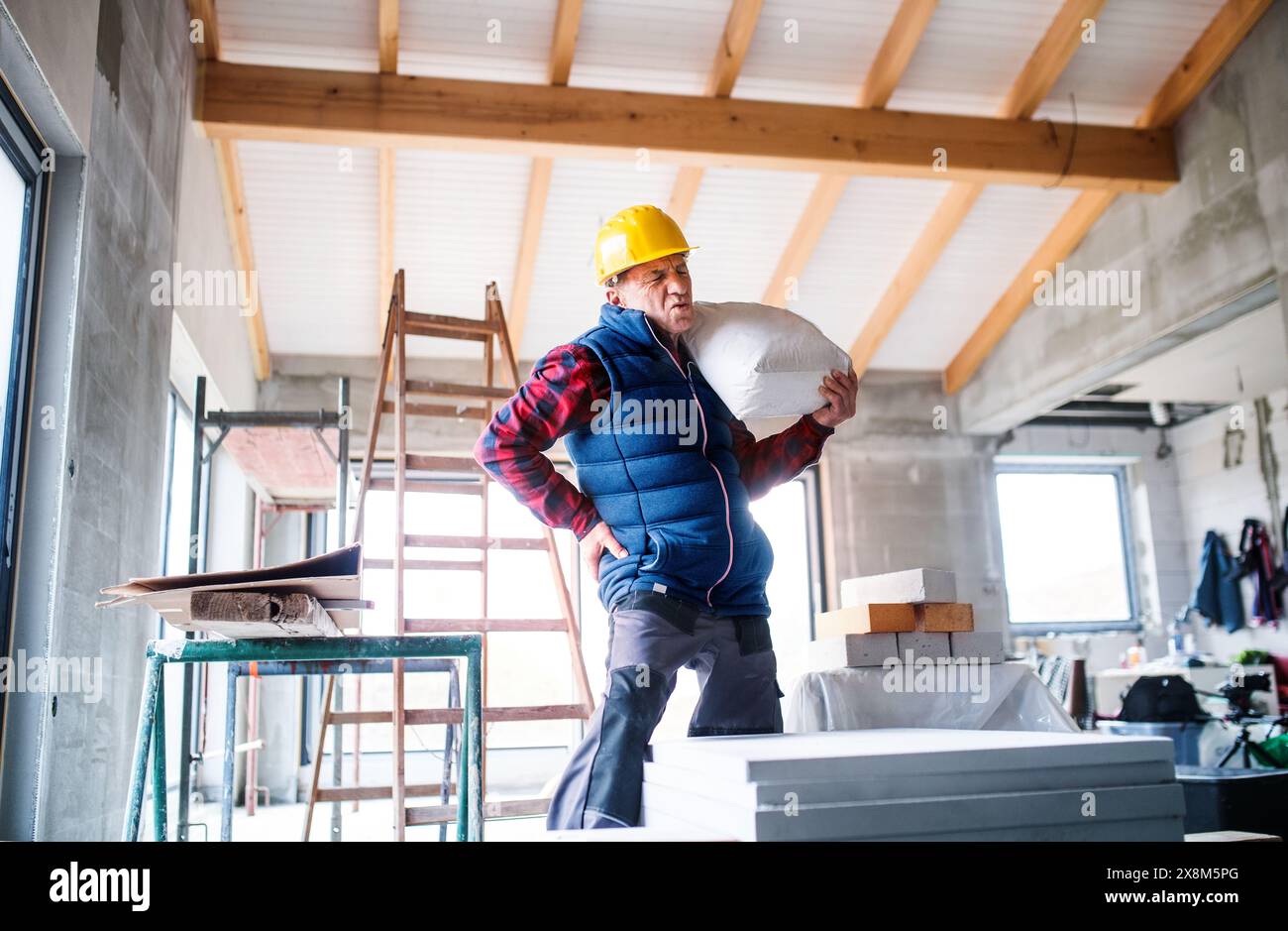 Older worker feeling pain in back after carrying heavy bag. Workrelated back injury Stock Photo