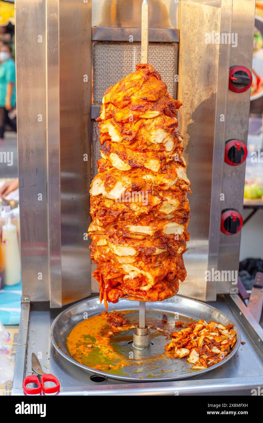 Shawarma meat is roasted on a vertical spit at a night market in Thailand. Street food. Stock Photo