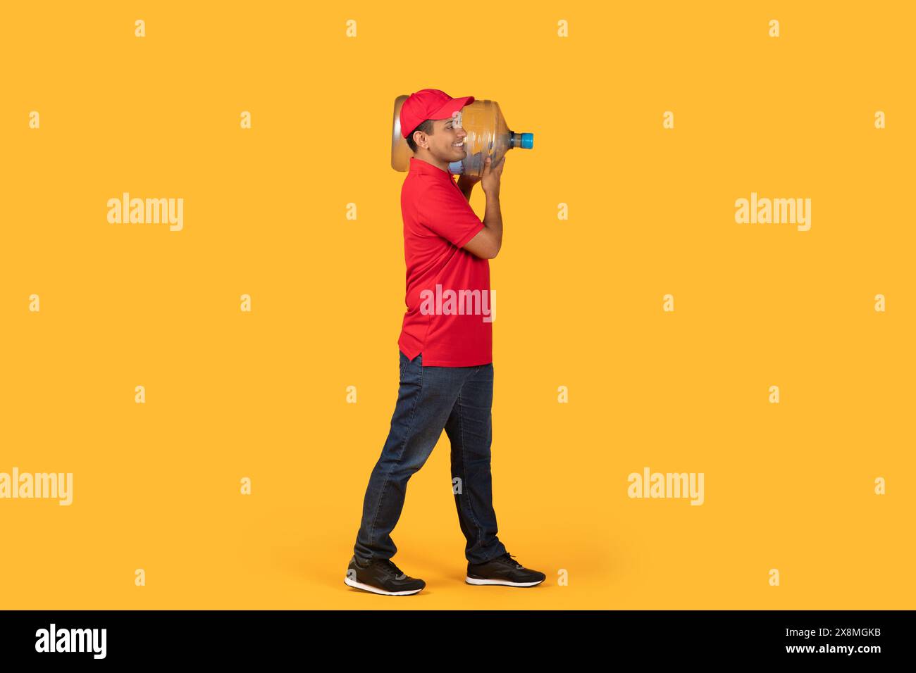 Man Carrying Water Gallon Against Yellow Background in Studio Setting Stock Photo