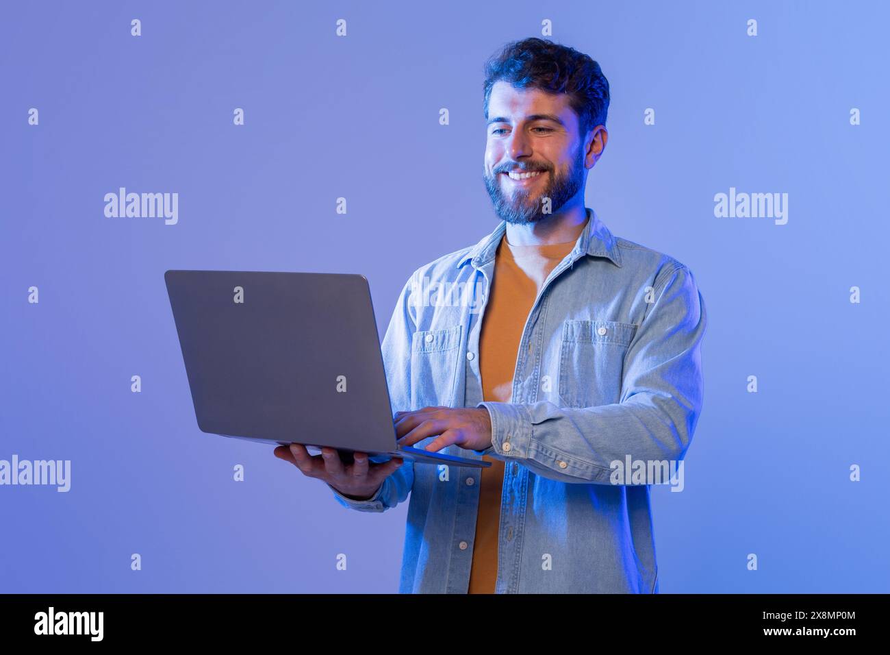 Man Smiles While Using Laptop Computer, Websurfing Stock Photo