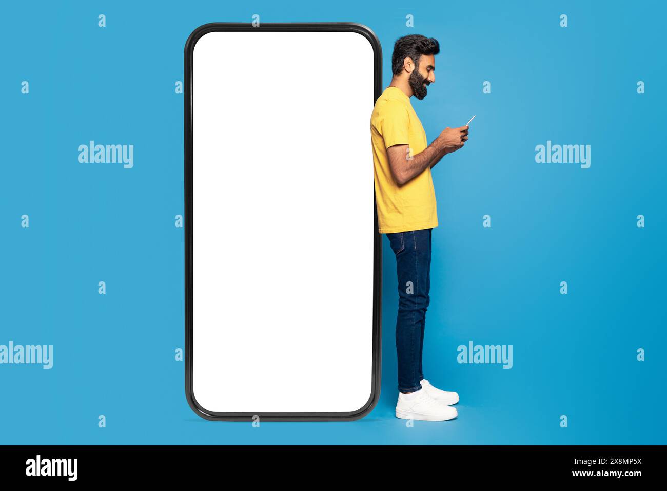 Young Man Using Smartphone Against Giant Phone Frame Stock Photo