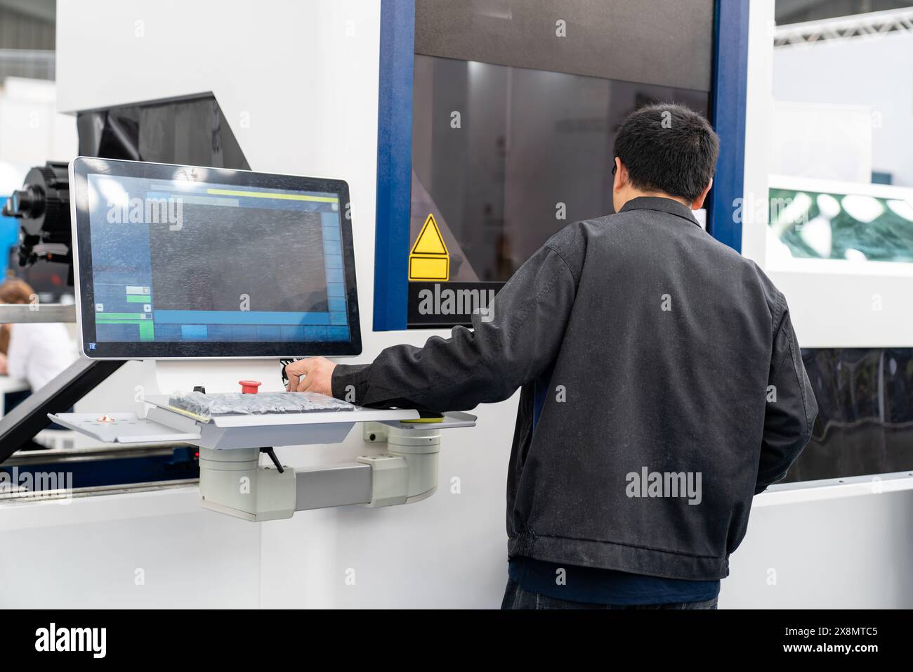 The operator operates an automatic machine for cutting metal. Smart factory. Stock Photo