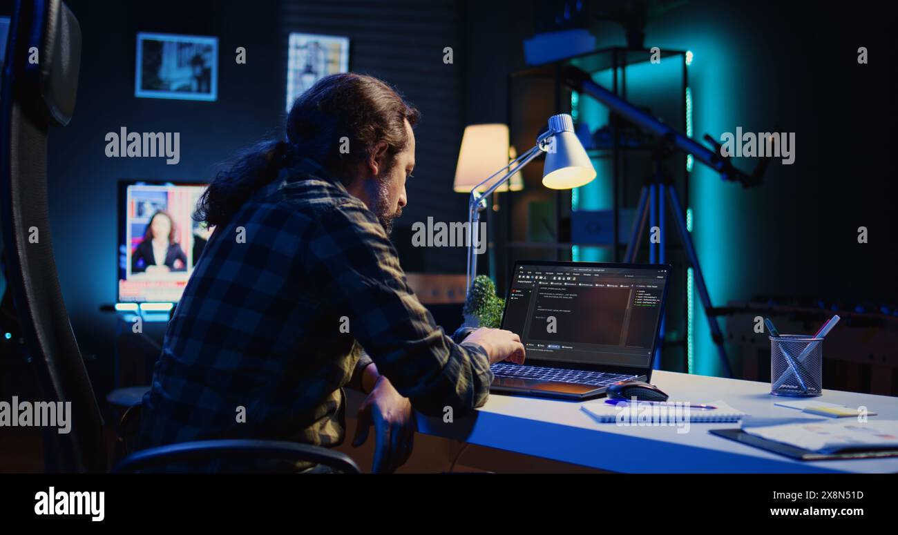 Experienced programmer writes code on laptop screen while in apartment office using Java programming languages. Developer remotely working on fixing database errors while working from home, camera B Stock Photo