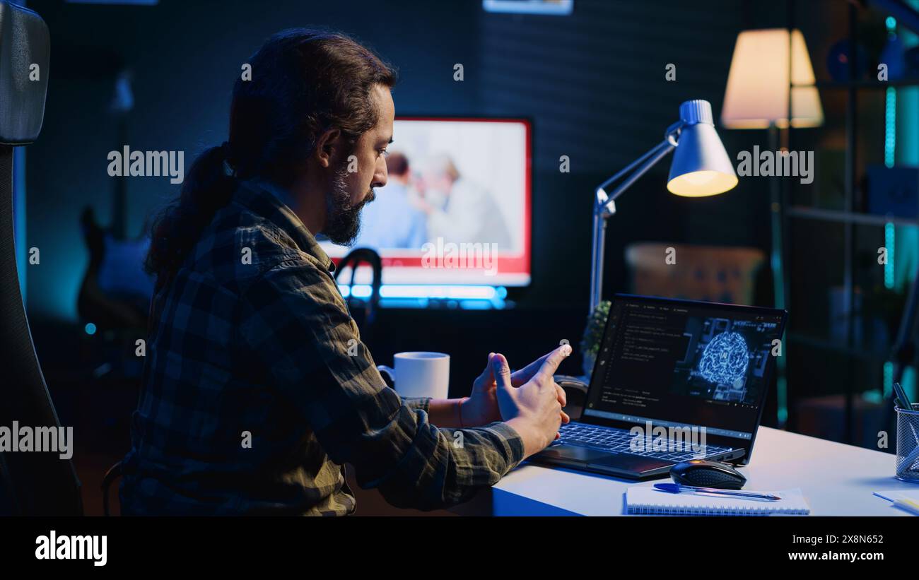 Programmer in living room office typing on keyboard, updating artificial intelligence neural networks, writing binary code scripts. Freelancing system administrator upgrading high tech AI Stock Photo