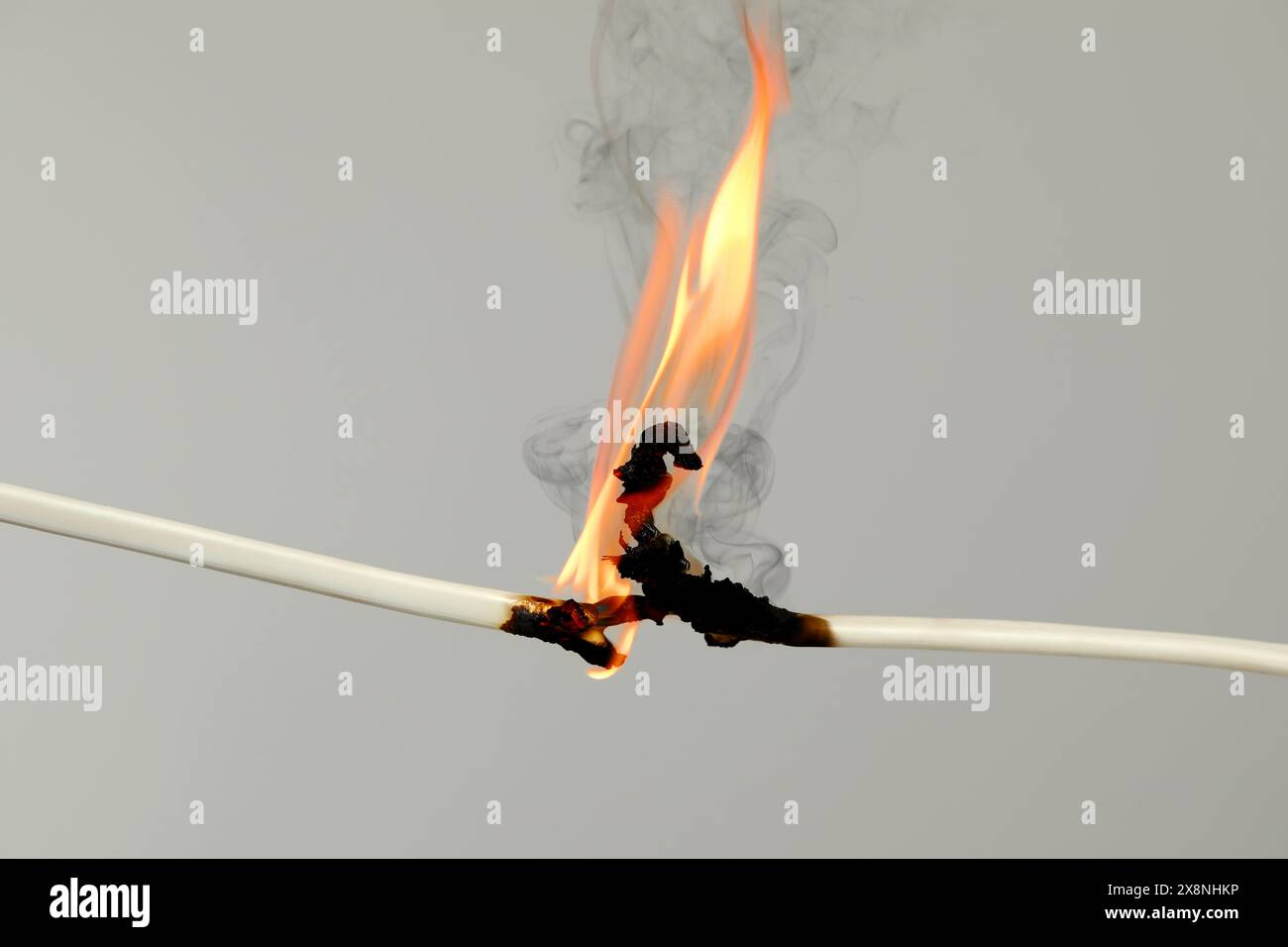 Electrical wire burning on light background, closeup Stock Photo
