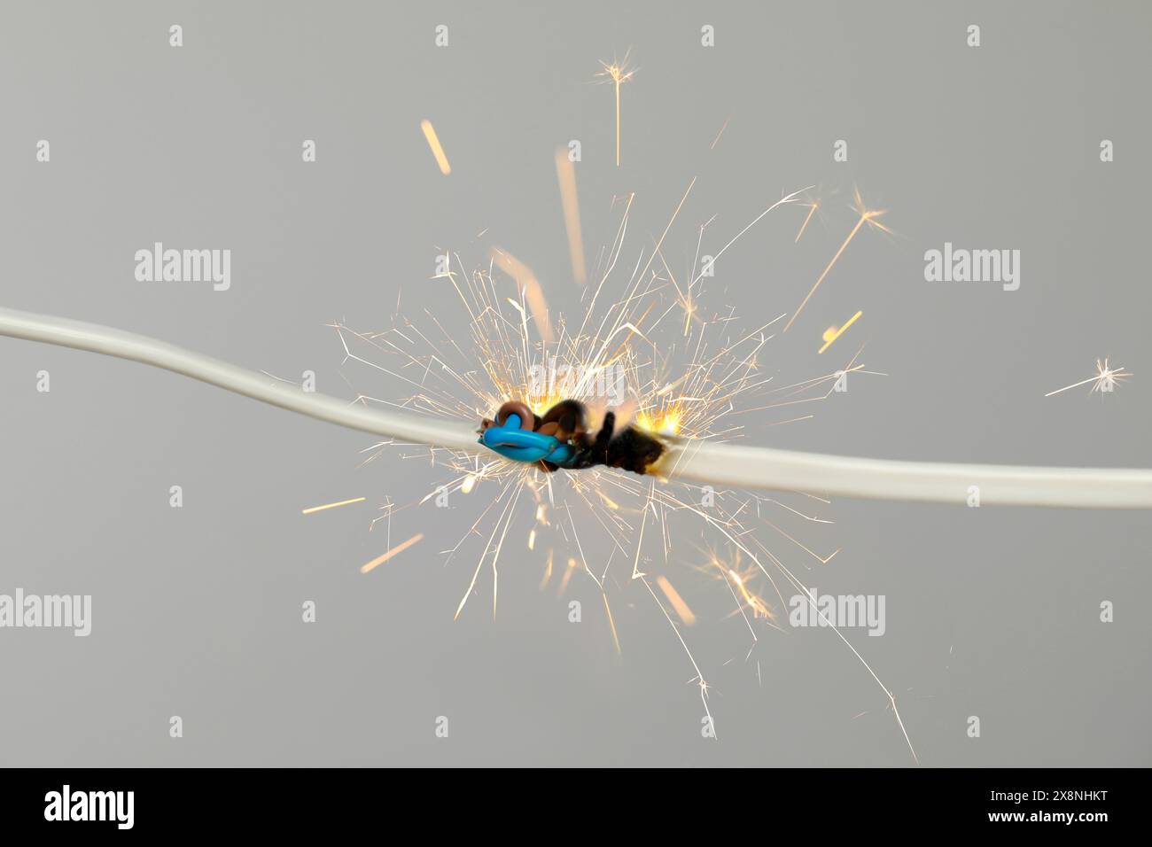 Sparking electrical wire on light background, closeup Stock Photo