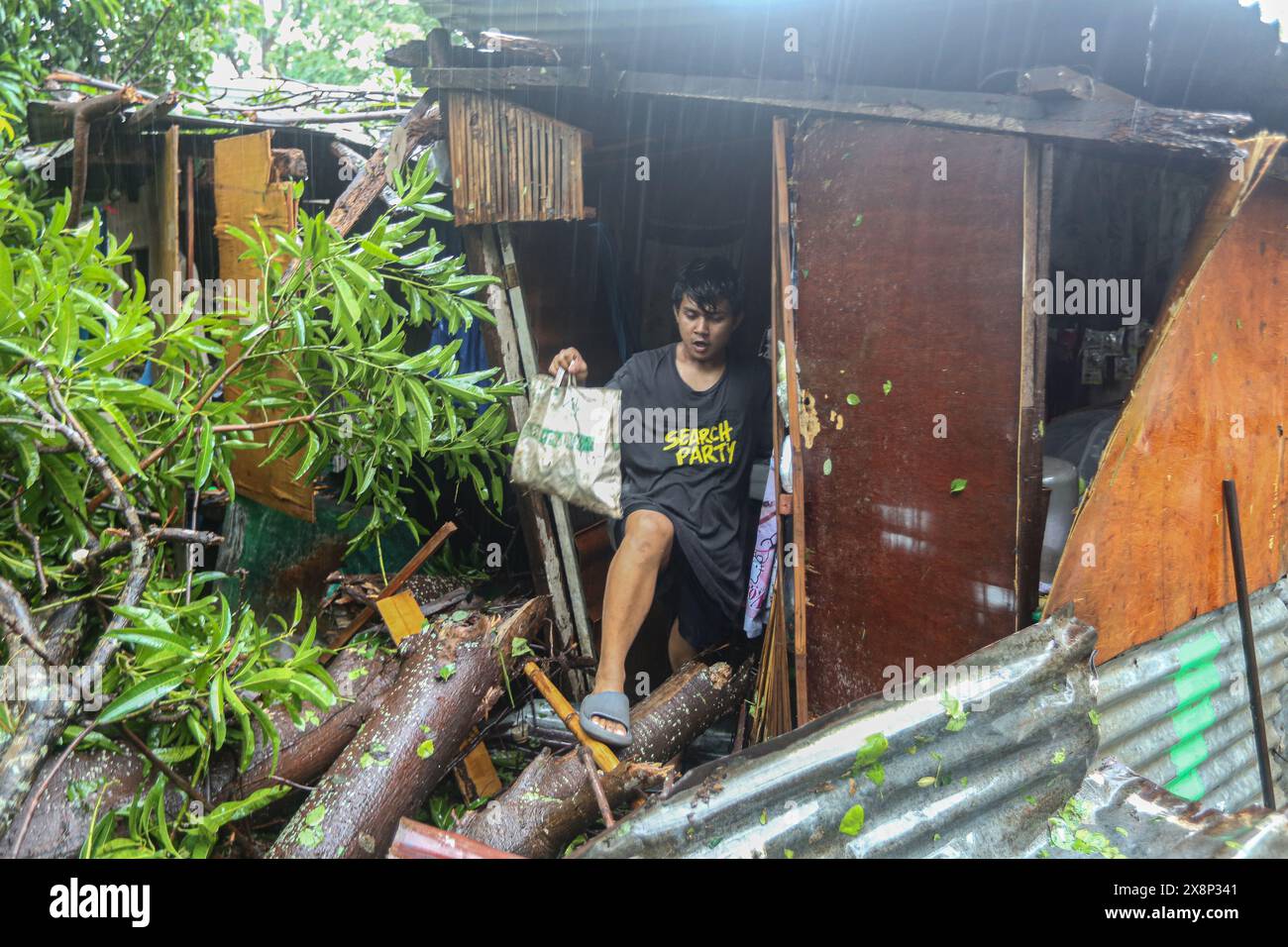 Laguna, Calabarzon, Philippines. May 26,2024: Filipino evacuating his house on which tree trunk fell 1m from baby's cradle. Forecast as severe tropical depression, first storm to hit the archipelago this year Aghon (Ewiniar) surprised Filipinos by devastating intensity: flooding, destructions, power/water cuts expected for days, tree falls, hundreds of rescued & families in evacuation centers. Reclassified as typhoon, gov announced humanitarian aid. In few hours, the country went from months-long heat records & extreme drought to torrential rains & floods. Credit: Kevin Izorce/Alamy Live News Stock Photo