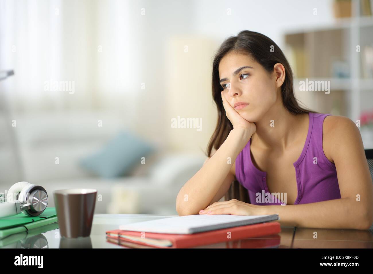 Apathetic student looking away sitting in the living room at home Stock Photo