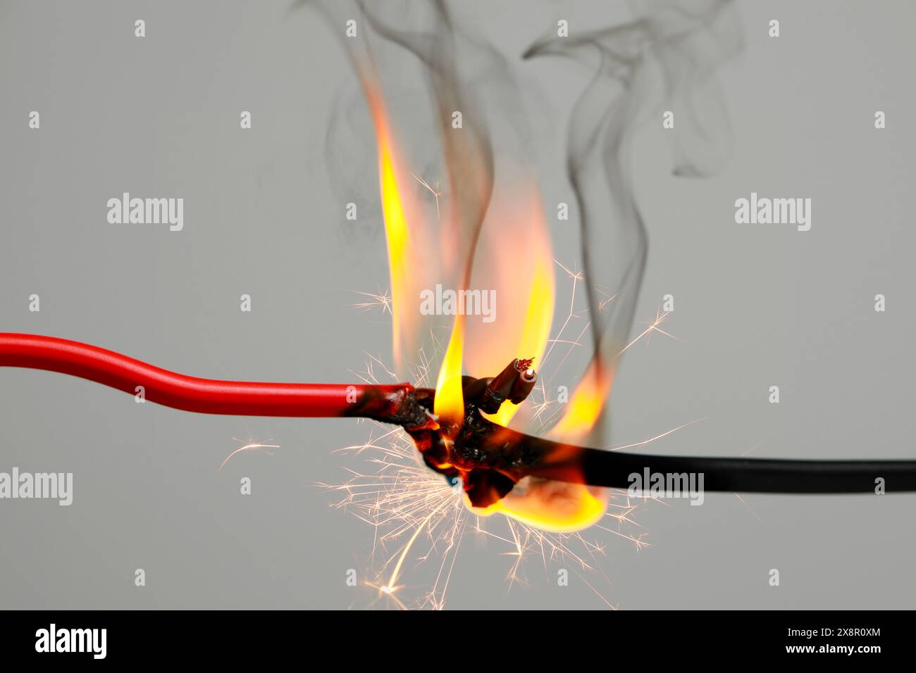 Electrical wire burning and sparking on light background, closeup Stock Photo