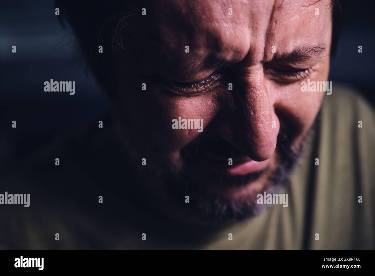 Man crying in dark room, sadness and grief concept, low key with selective focus Stock Photo