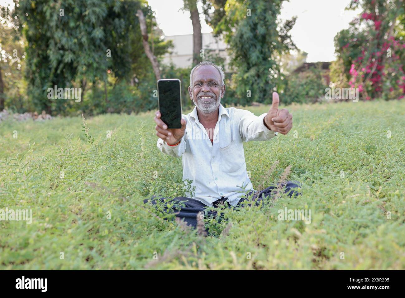 Indian chickpeas Farming , happy indian farmr holding mobile phone in hands, poor happy farmer Stock Photo