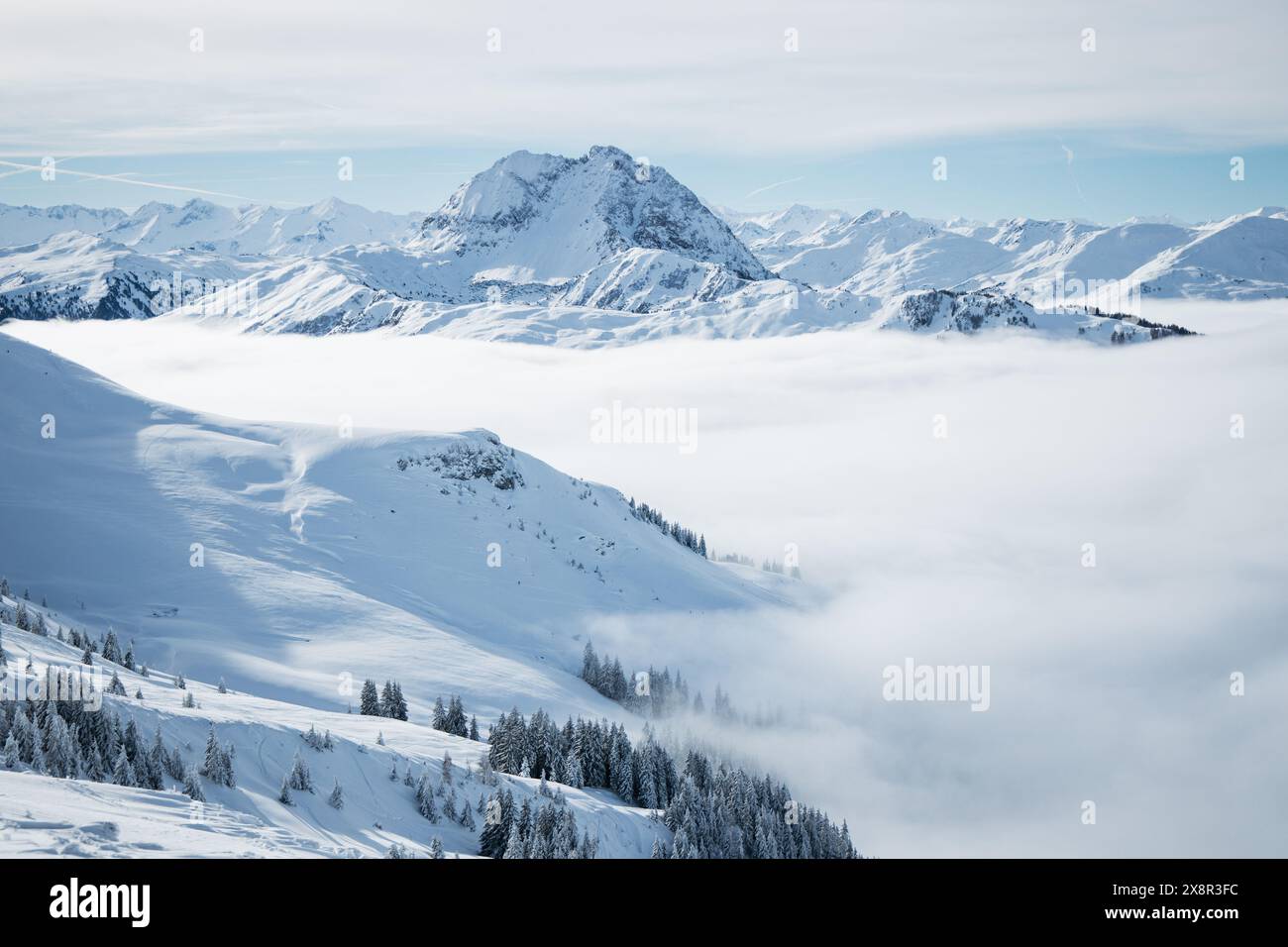 Snow-covered mountains under a clear sky with misty valleys Stock Photo