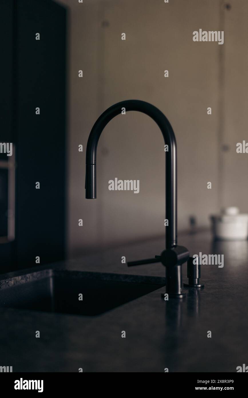 Modern black faucet in a minimalist concrete kitchen setting Stock Photo