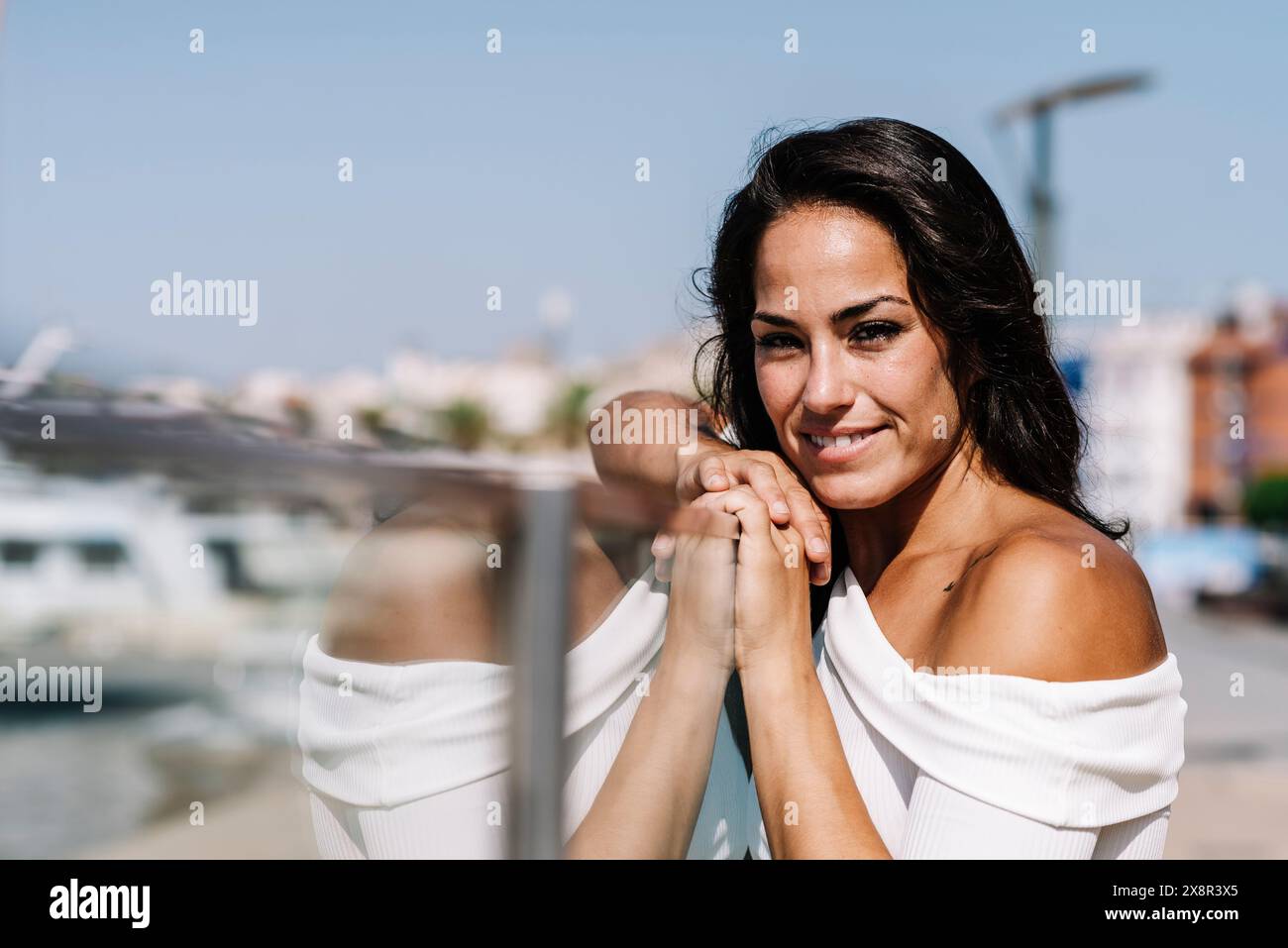 Dreamy young woman leaning on fence while looking camera Stock Photo