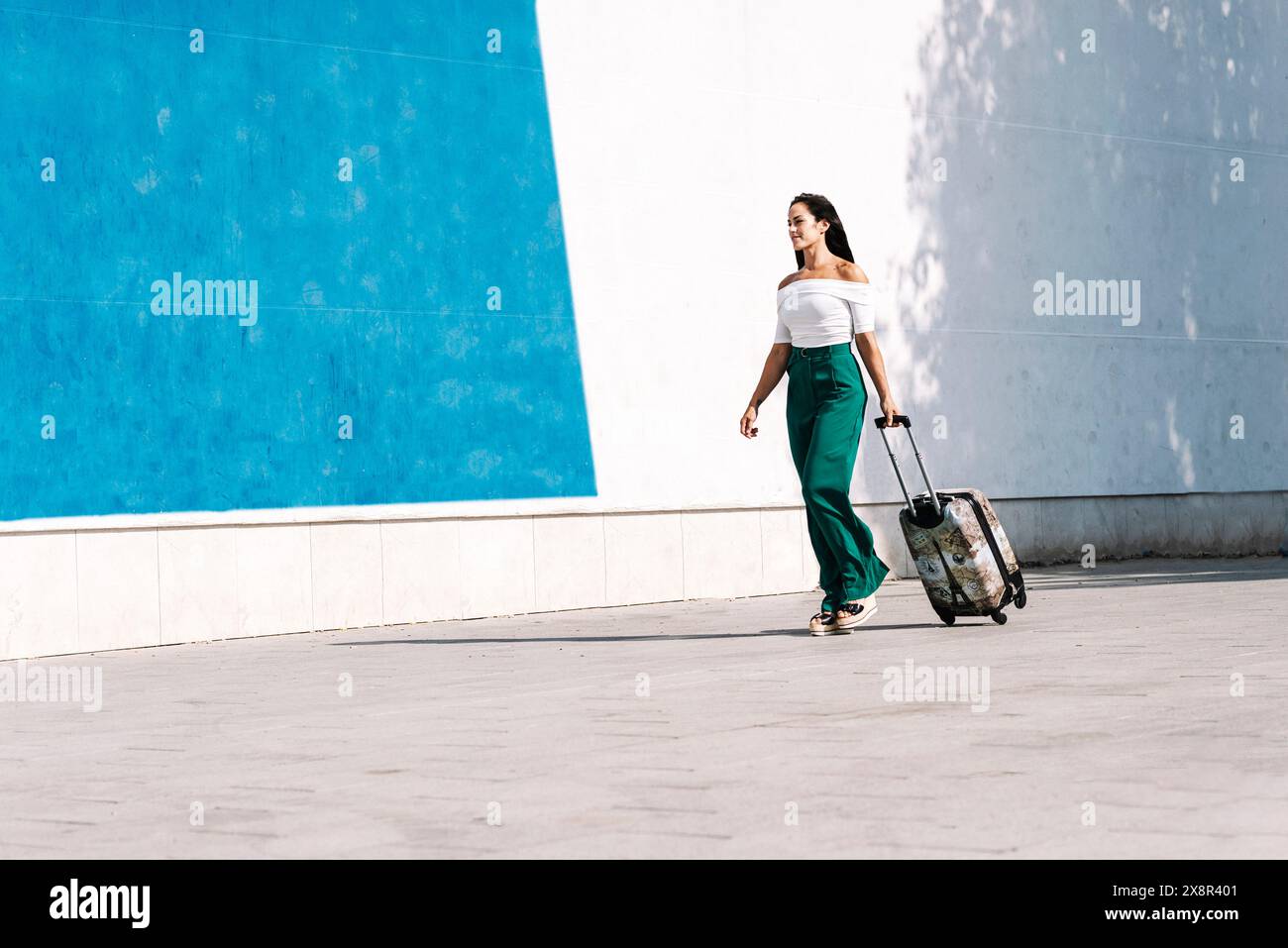Young female tourist carrying a baggage while walking in street Stock Photo