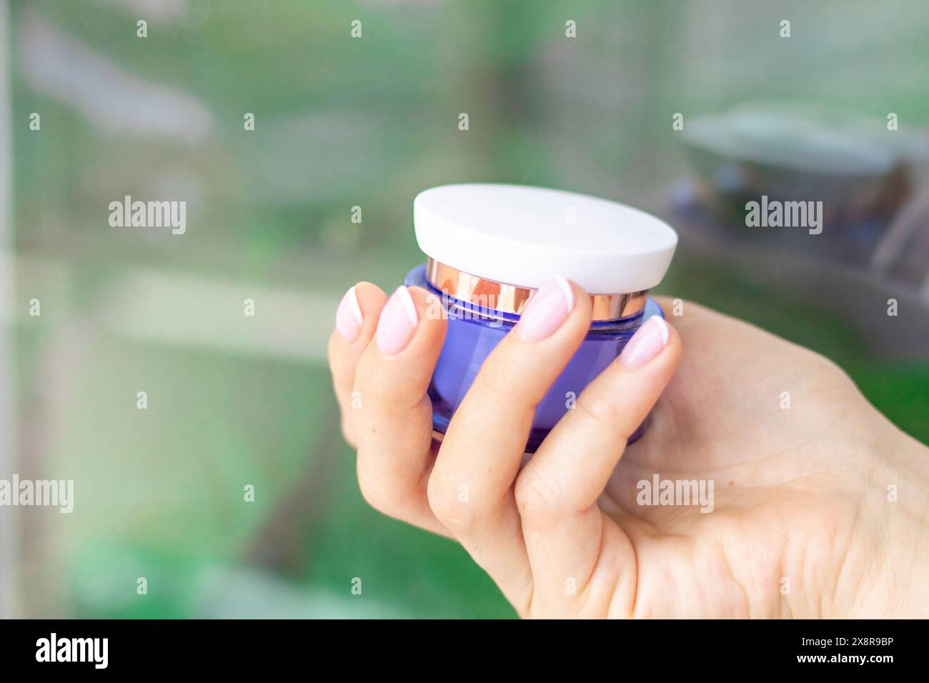 Shot of the beautiful woman's hand holding bottle of skin care product. Stock Photo