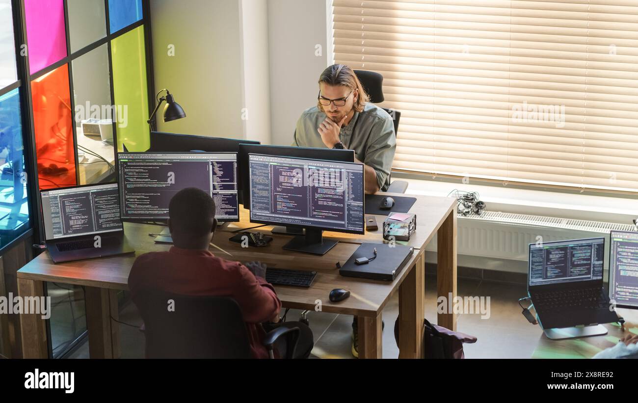Diverse Colleagues Writing Code on Desktop Computers With Professional Multiple Monitors Setup. Software Development Department Working on Software as a Service Platform For Business Clients. Stock Photo