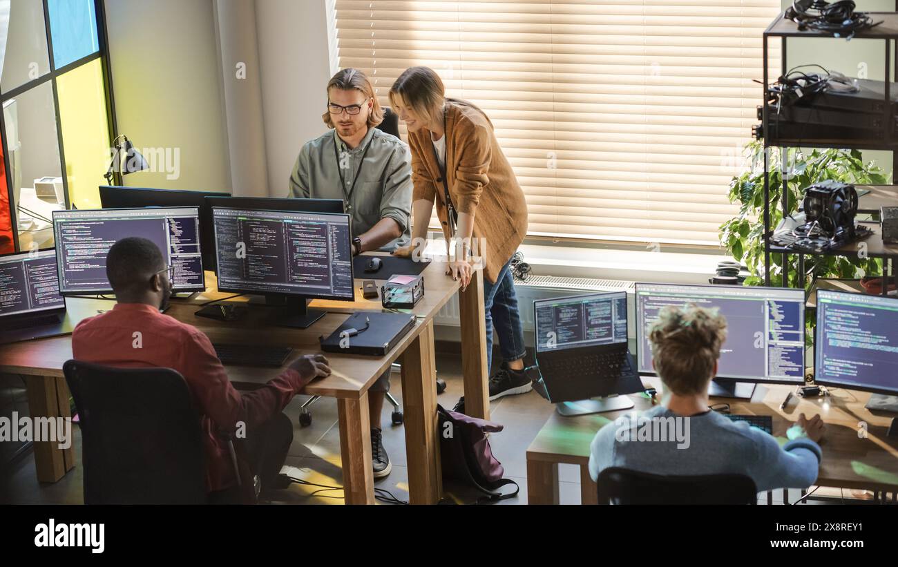 Creative Office: Diverse Colleagues Coding on Desktop Computers With Multiple Monitors. Female Project Manager Talks to Male Team Lead While Junior Developers Working on Mobile Application. Stock Photo