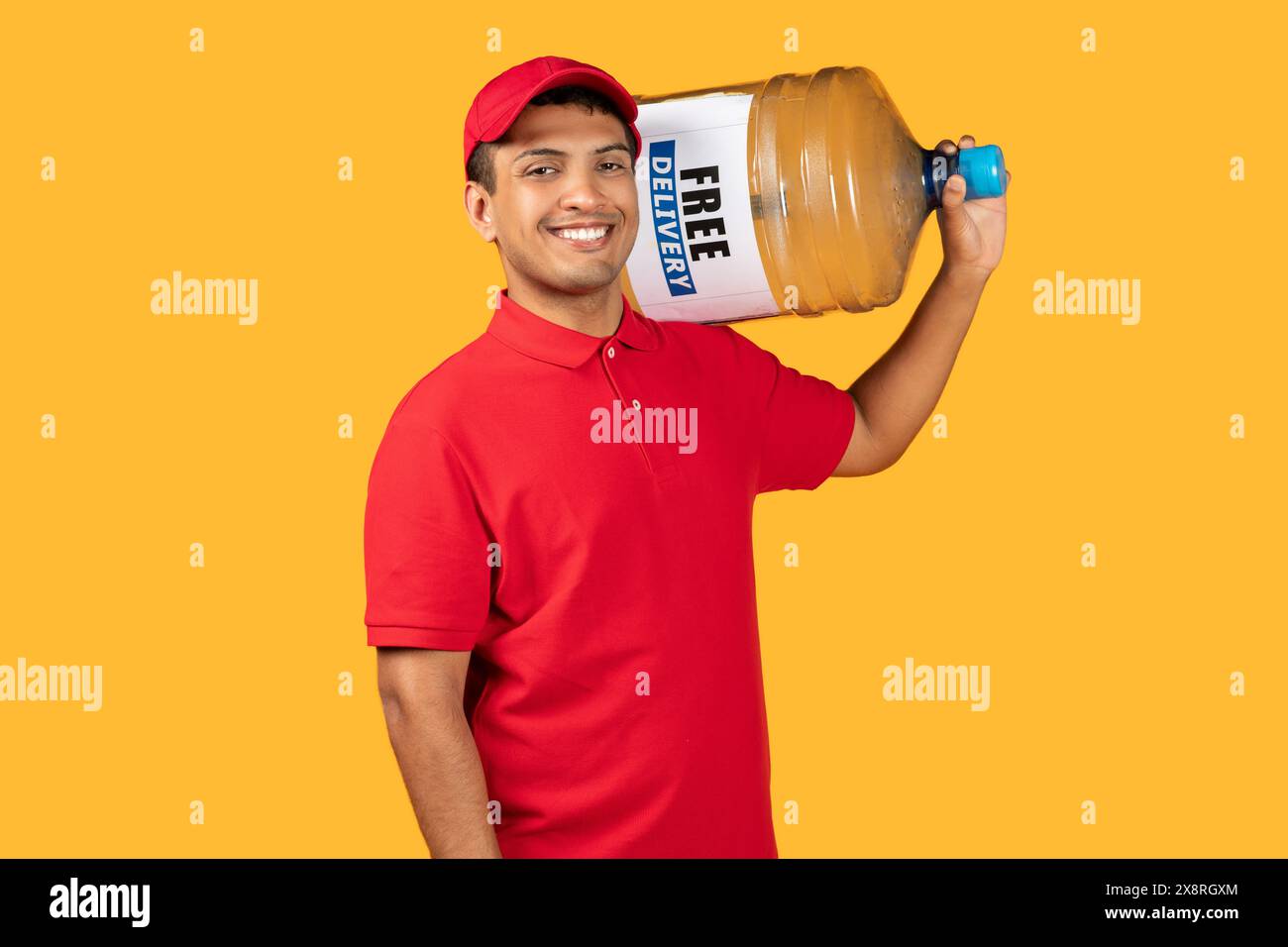 Smiling Delivery Worker in Red Uniform Holding Large Water Jug Stock Photo