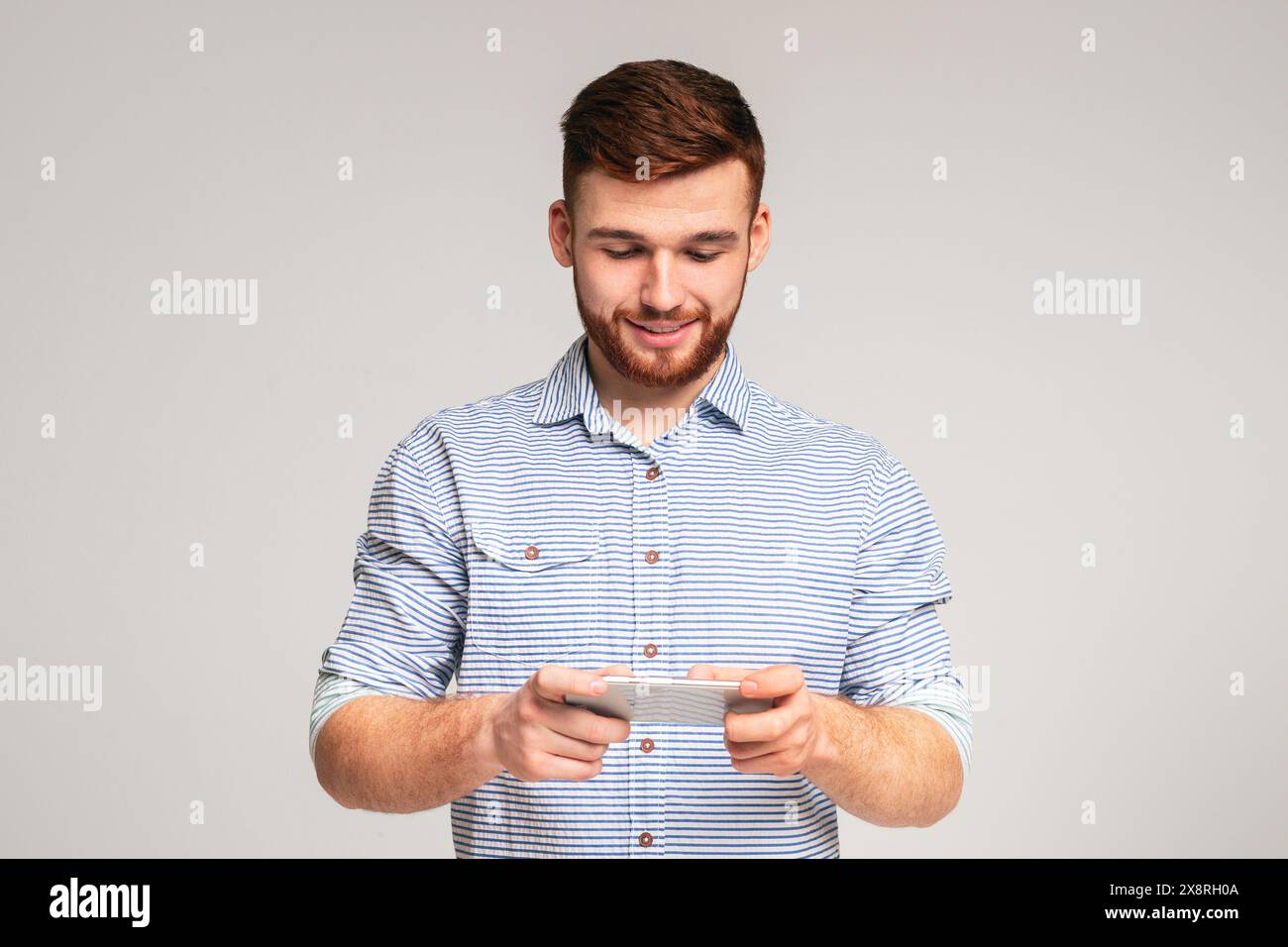 Young guy playing games on his phone and having fun Stock Photo