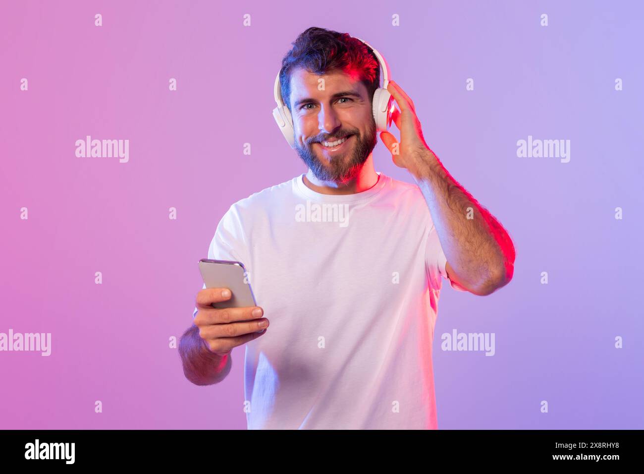 Man Wearing Headphones and Holding Cell Phone Stock Photo