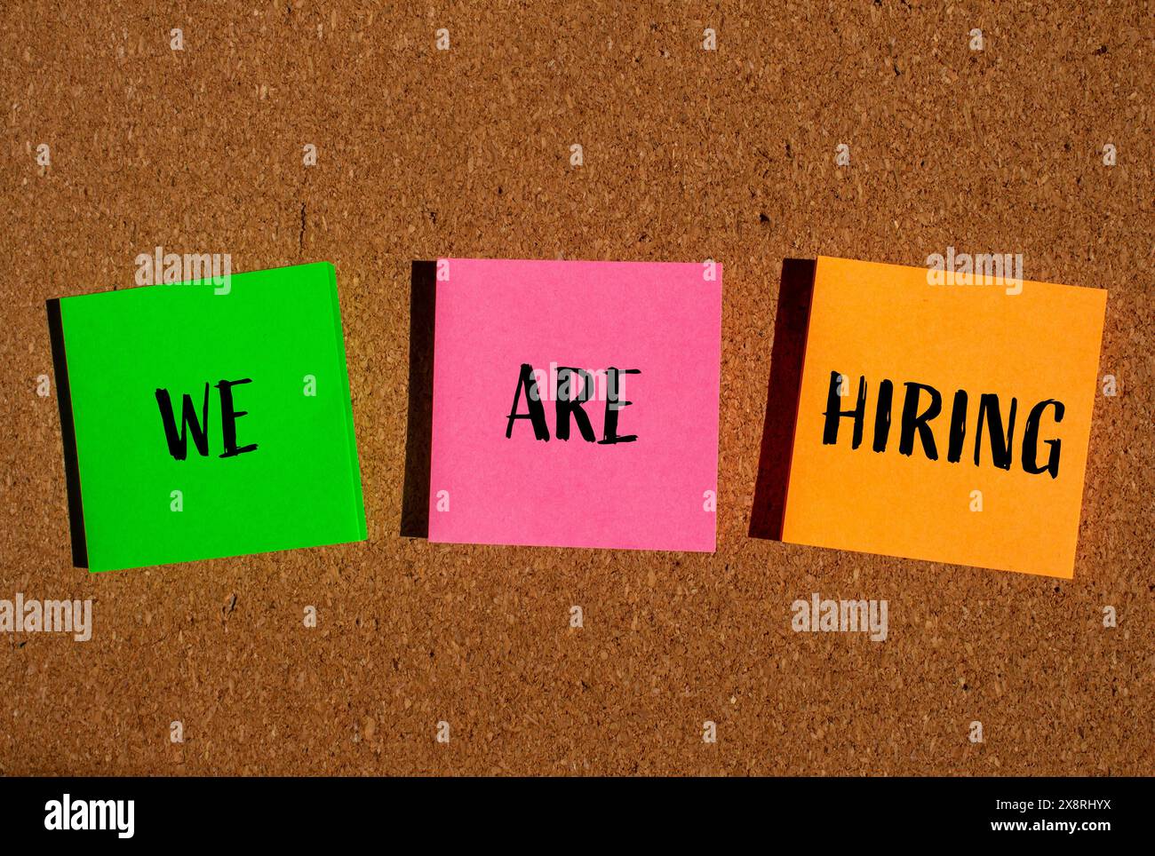 We are hiring words written on colorful papers with brown background ...