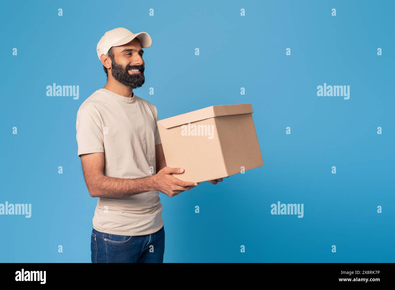 Bearded Man Holding a Brown Box Against Blue Background Stock Photo