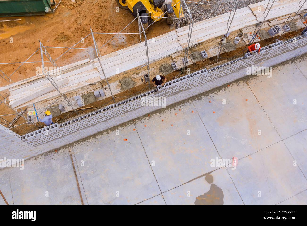 Mason Using Blocks On construction site, mason makes concrete wall using cement blocks ...