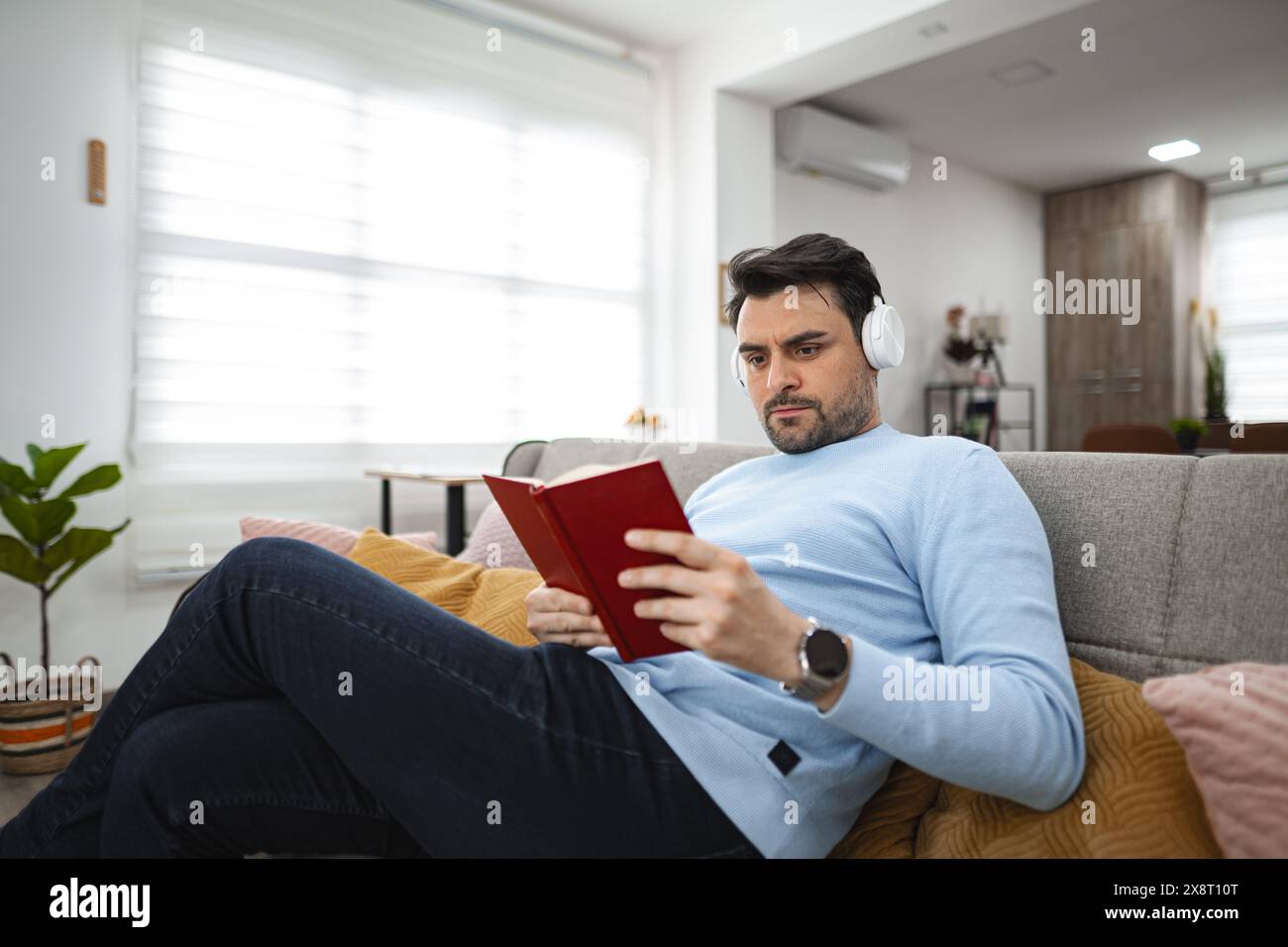 Man Reading Book on Couch Stock Photo