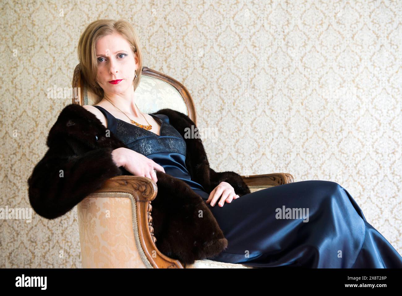 Portrait woman with style Tilburg, Nederland, Adult caucasian woman wearing evening dress, while sitting in a chair and getting ready to go out to a classical concert. MRYES Tilburg Gerard van Swietenstraat Noord-Brabant Nederland Copyright: xGuidoxKoppesxPhotox Stock Photo