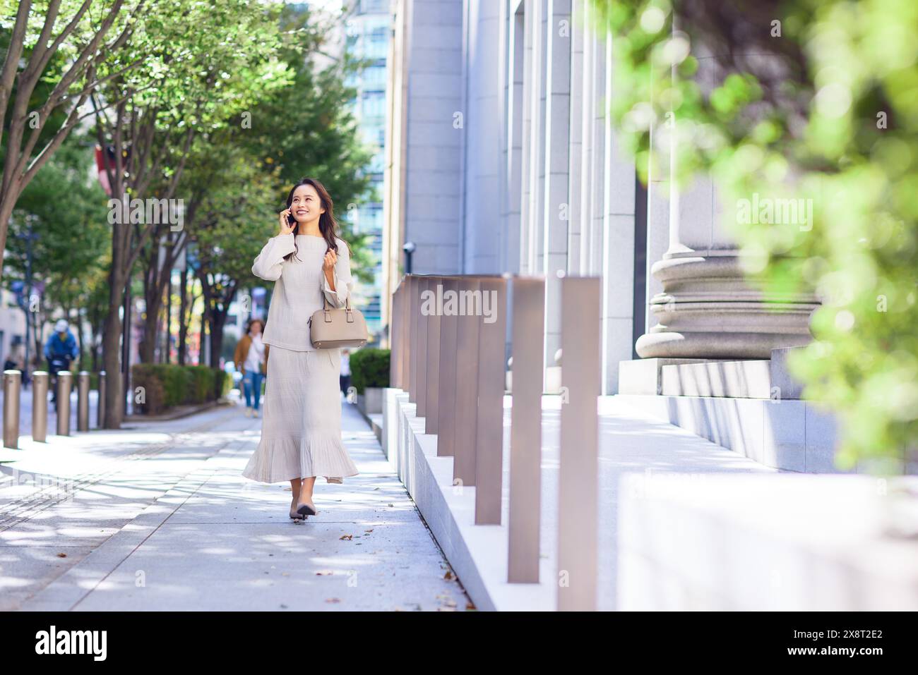 Japanese woman in a white dress walking down a sidewalk Stock Photo - Alamy