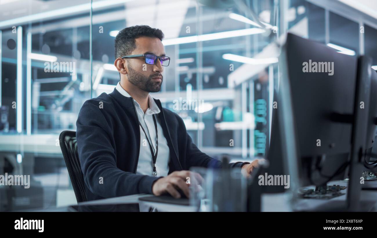 Portrait of Multiethnic Industrial Engineer Developing 3D Model of a Circuit Motherboard on Computer CAD Software in a Factory. Modern Technological Research and Development Center. Stock Photo