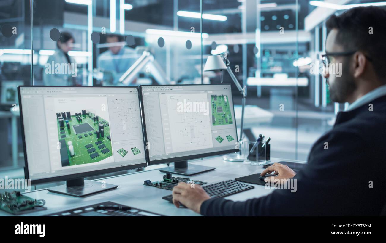 Portrait of a Handsome Hispanic Industrial Engineer Developing 3D Model of a Circuit Motherboard on Computer CAD Software in a Factory. Modern Technological Research and Development Center. Stock Photo