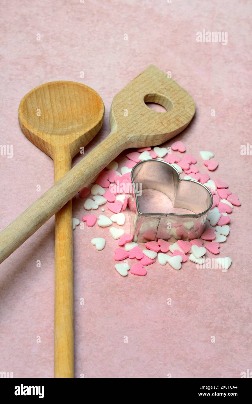 Cooking spoon and heart-shaped cookie cutter with sugar hearts Stock Photo
