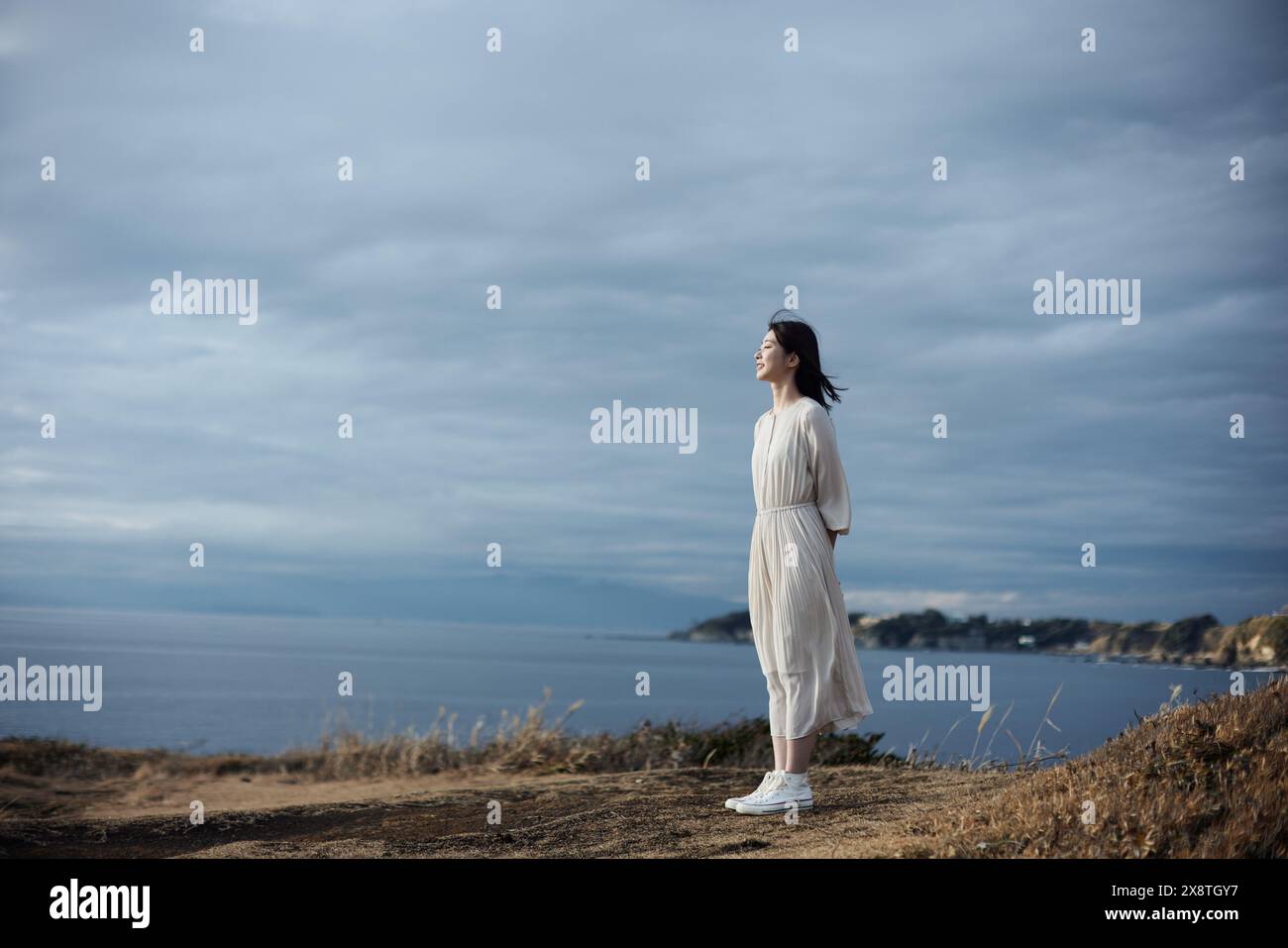 Japanese woman in a white dress standing on a hill overlooking the ...