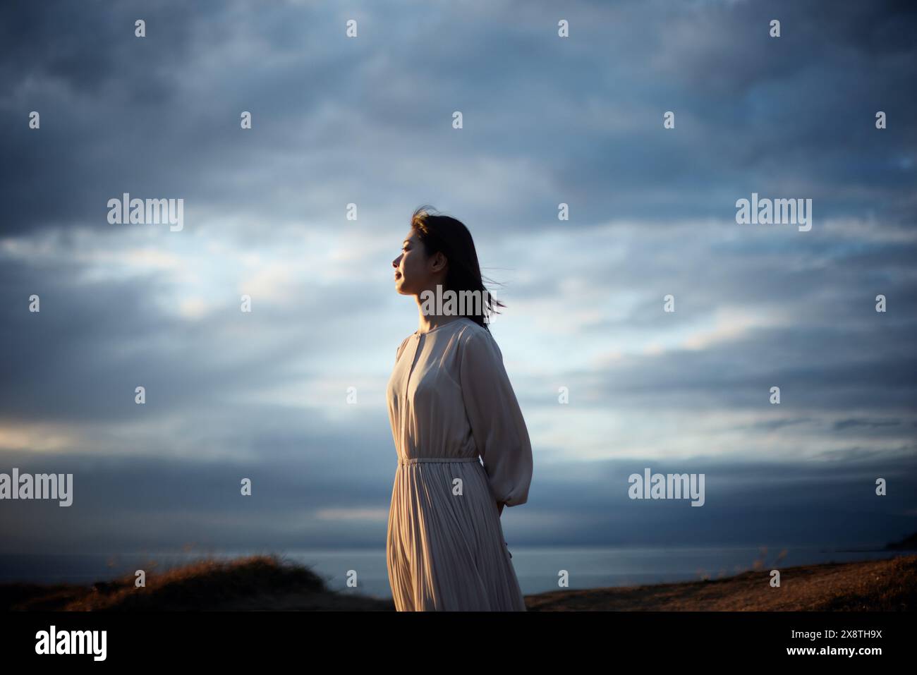 Japanese woman in a white dress standing on a hill overlooking the ...