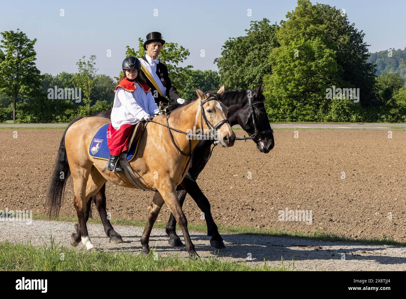 A horseman and a little altar boy in red and white costumes at the ...