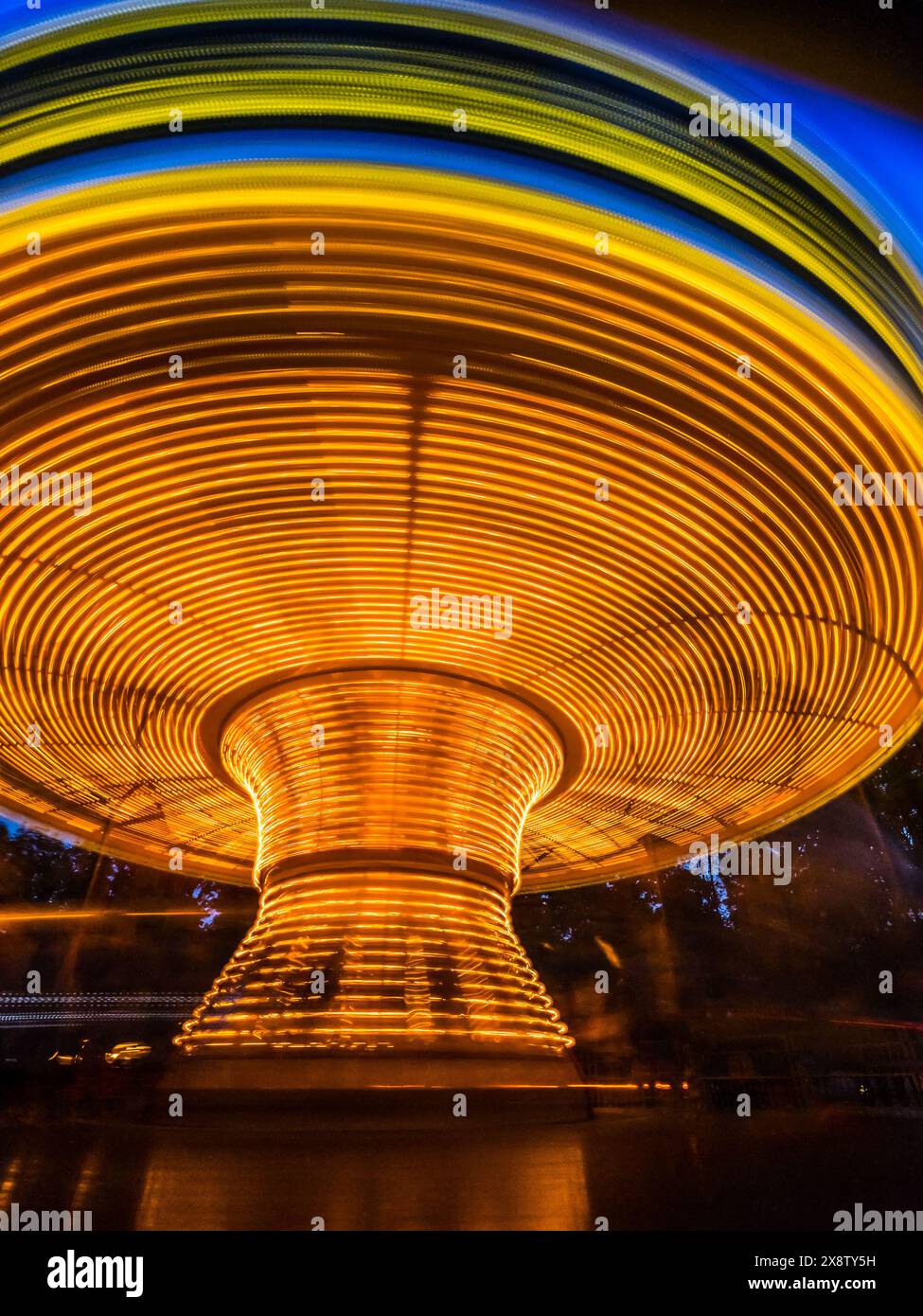 Abstract long exposure of bright rotating merry go carousel at night Stock Photo