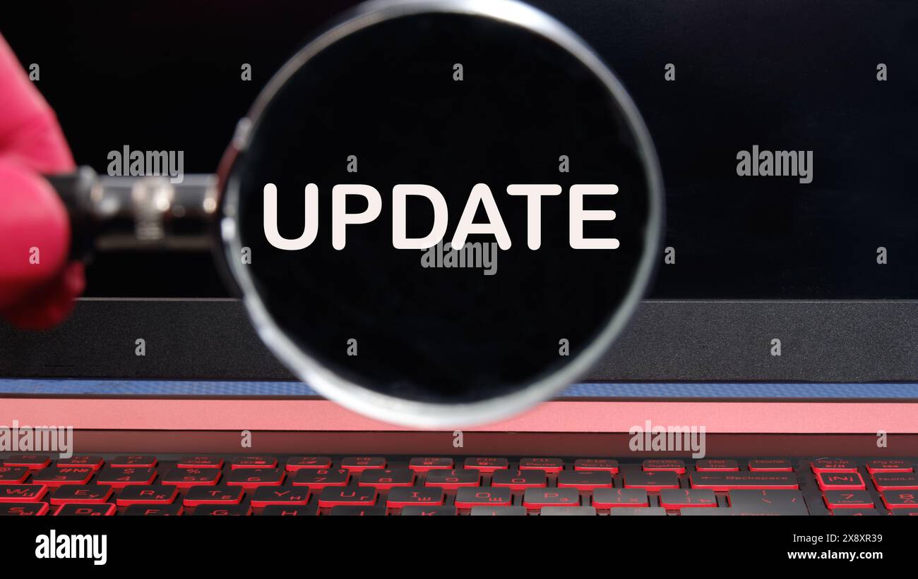 Finance and economics concept. The text is written UPDATE text appeared through a magnifying glass on a dim laptop screen Stock Photo