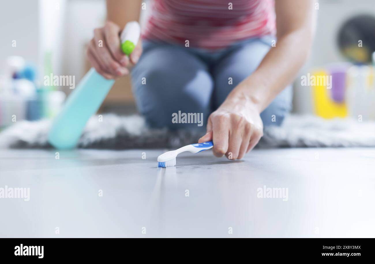 Careful woman cleaning the bathroom floor, she is scrubbing the joints