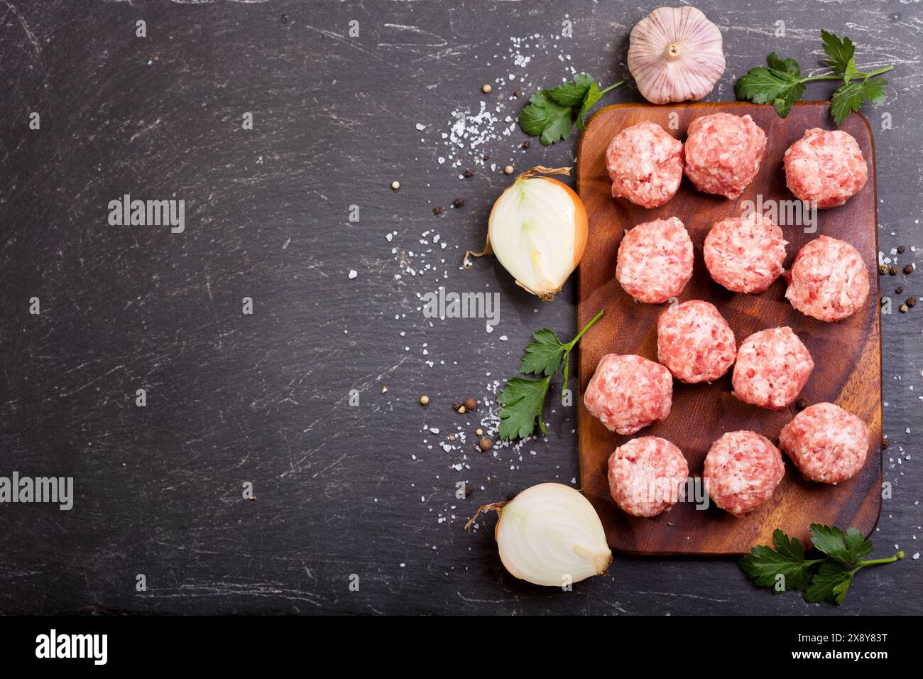 fresh raw meatballs with vegetables on dark table Stock Photo
