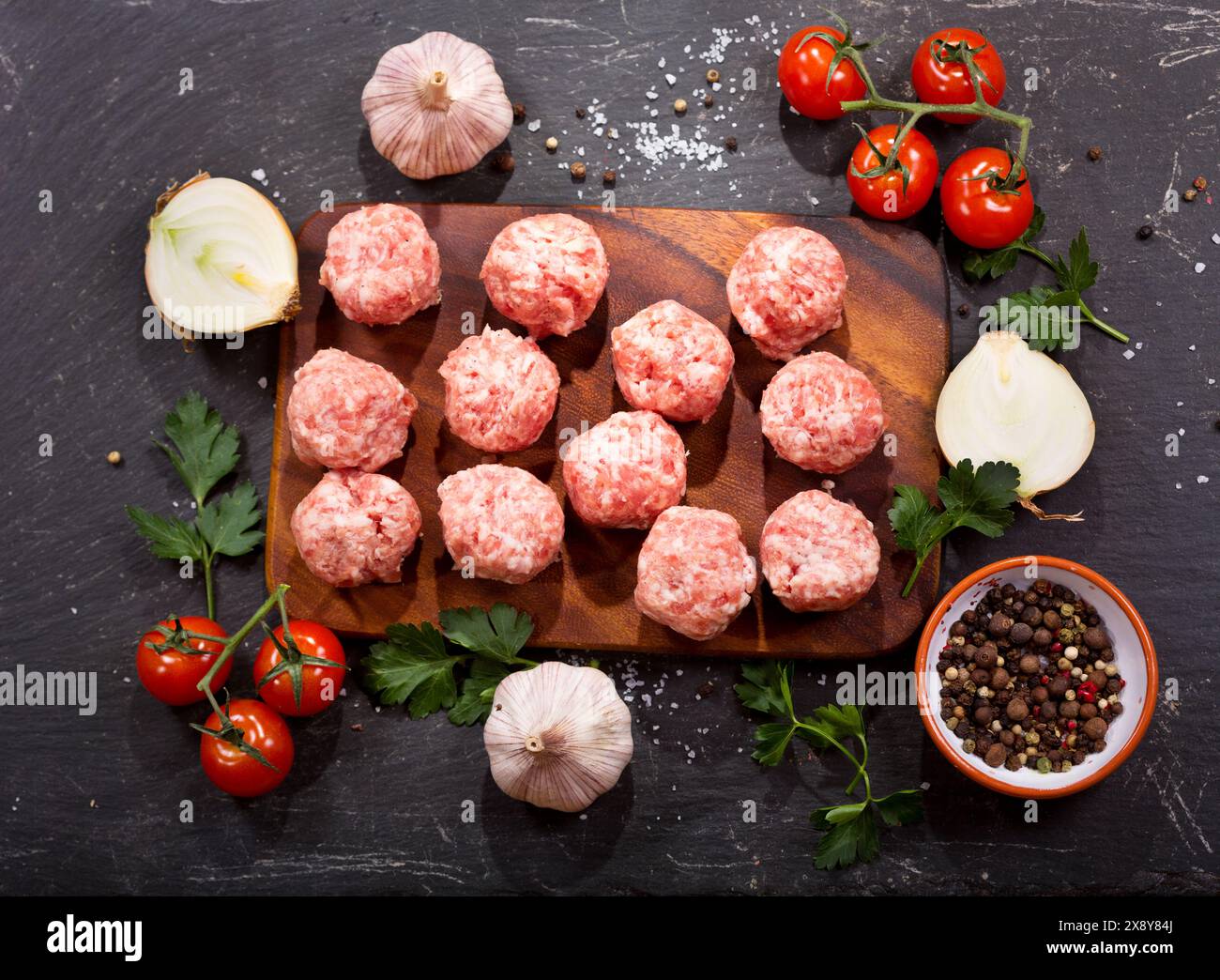 fresh raw meatballs with vegetables on dark table Stock Photo